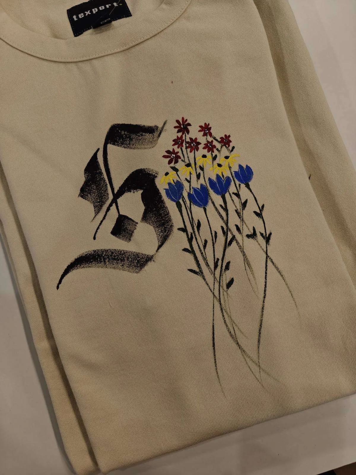 Calligraphy initial with painted wildflowers on a T-shirt