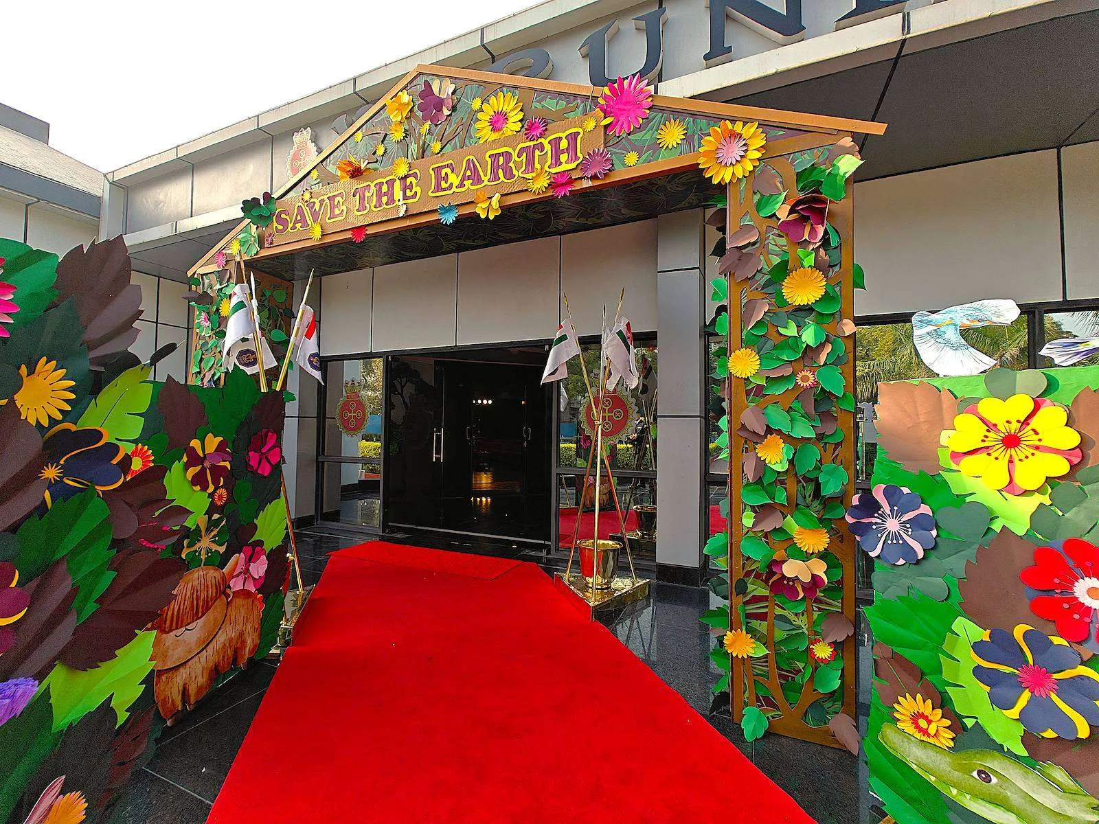 Save the Earth paper-flower archway with a red carpet at Varunika