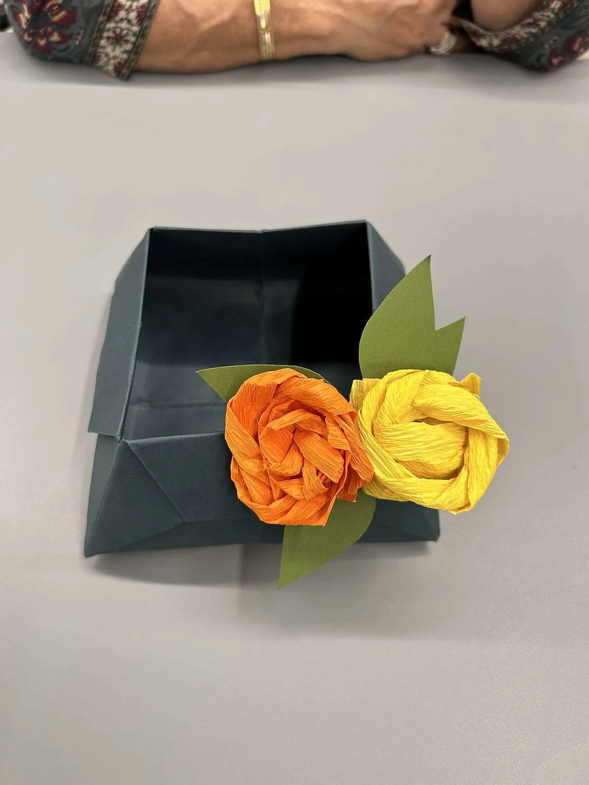 Orange and yellow paper roses in a folded paper box