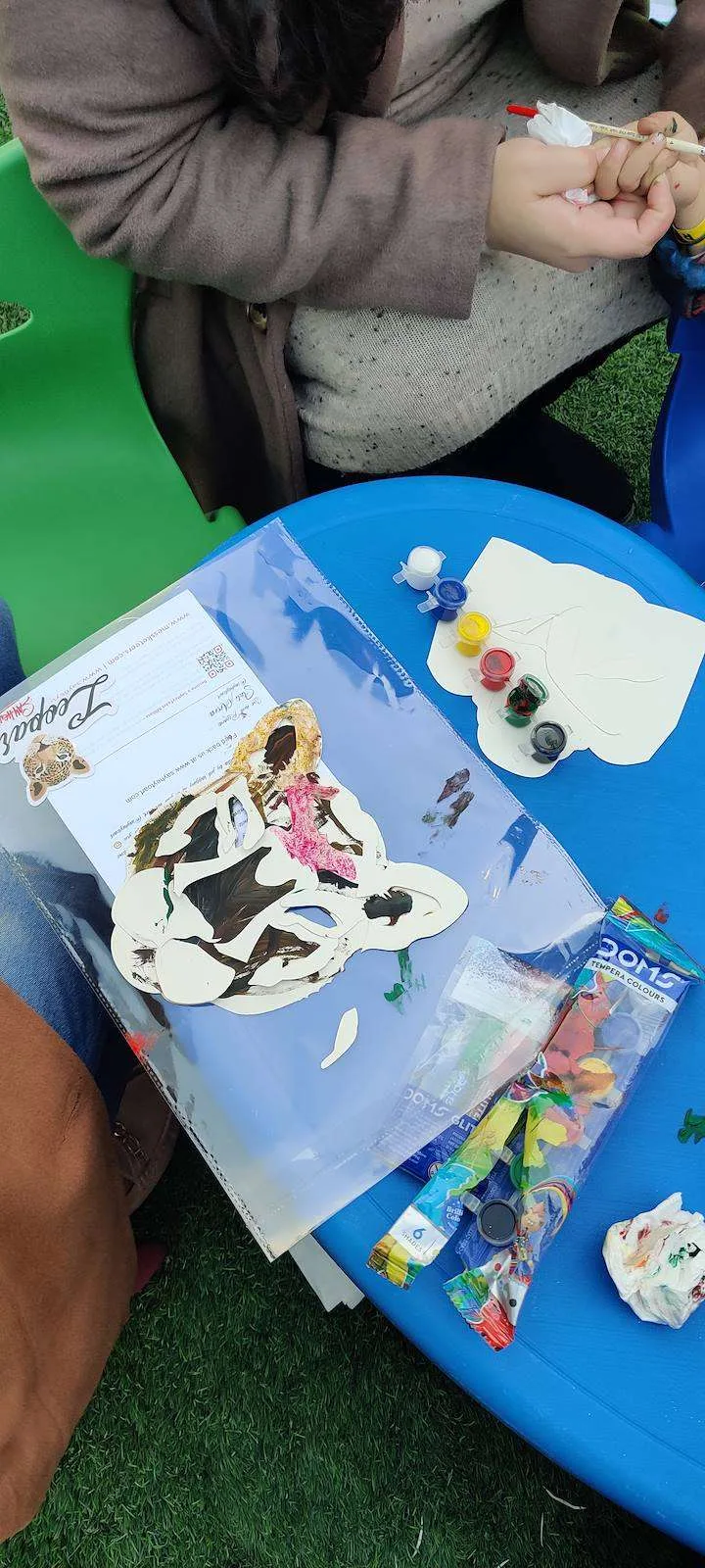 Children colouring paper masks at a blue table