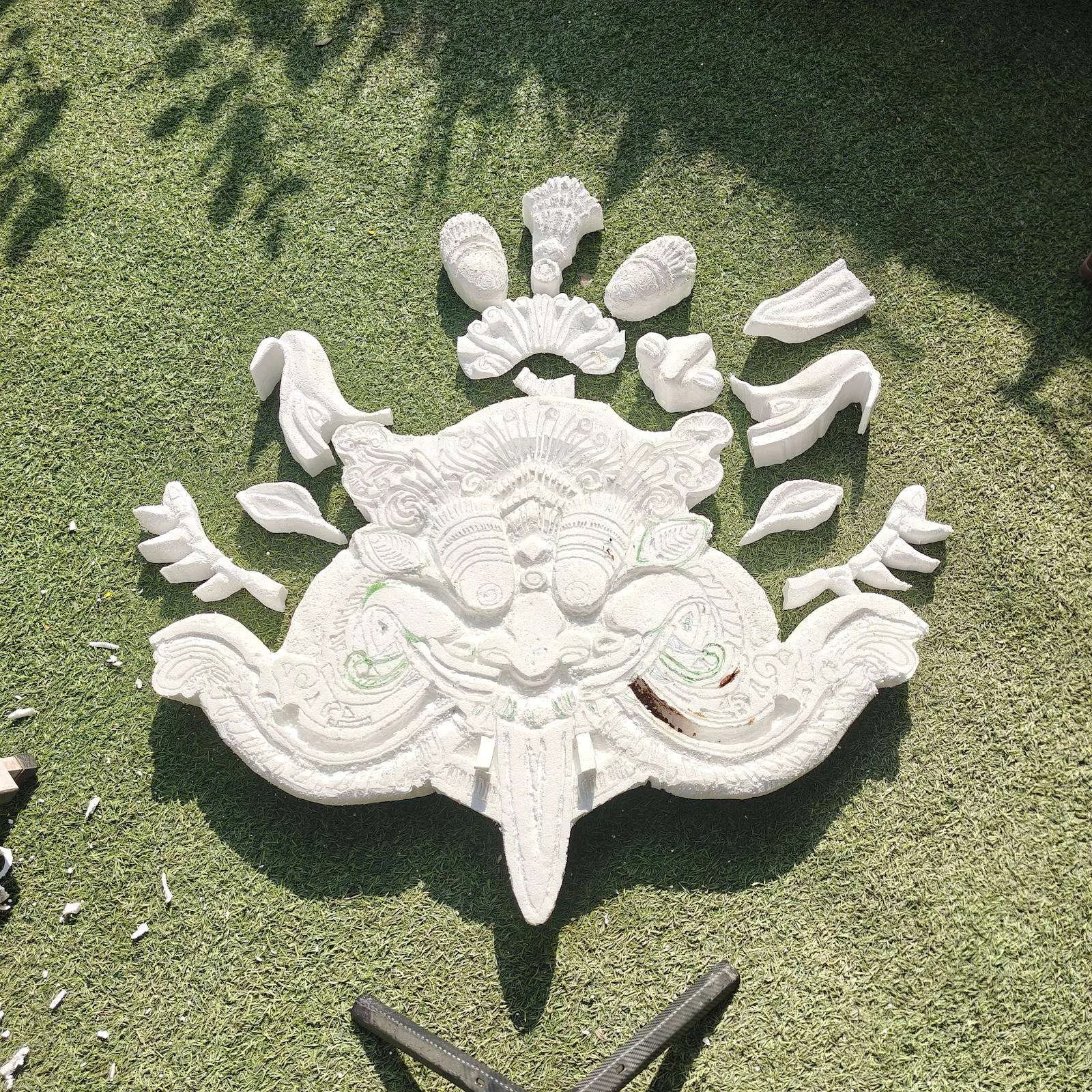 Unpainted carved Kirtimukh form drying on grass