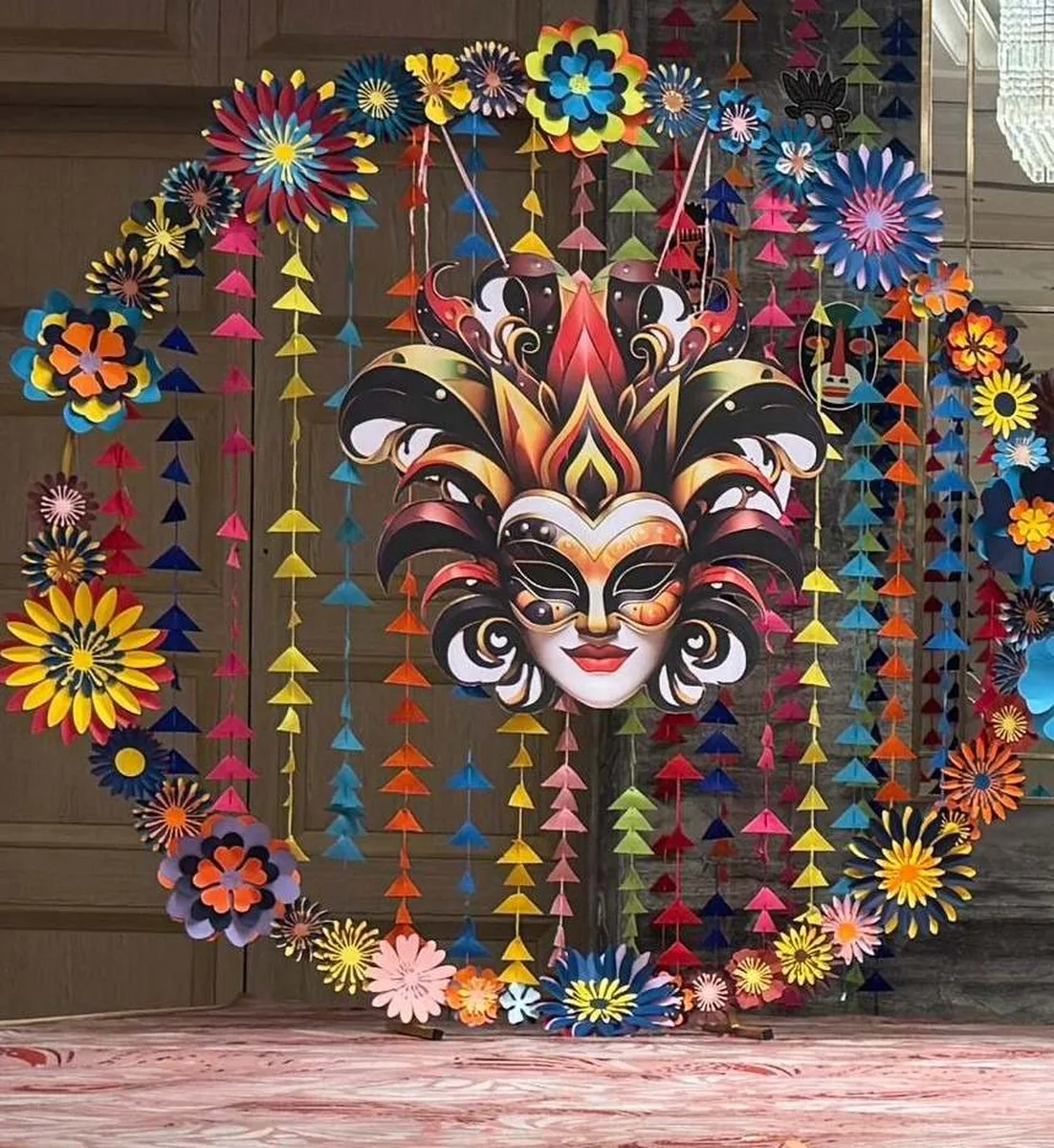 Circular carnival mask paper-art panel with layered paper flowers
