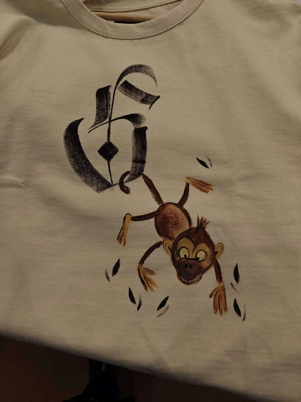 Calligraphy initial with a painted monkey on a T-shirt