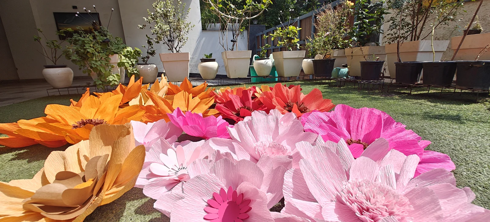 Outdoor arrangement of giant orange and pink crepe paper flowers