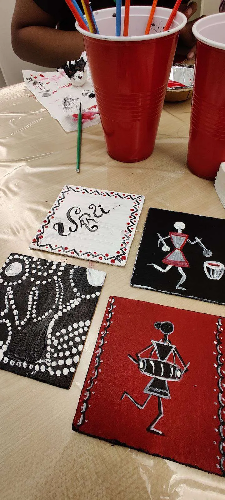 Black, red and kraft painted coasters on a workshop table