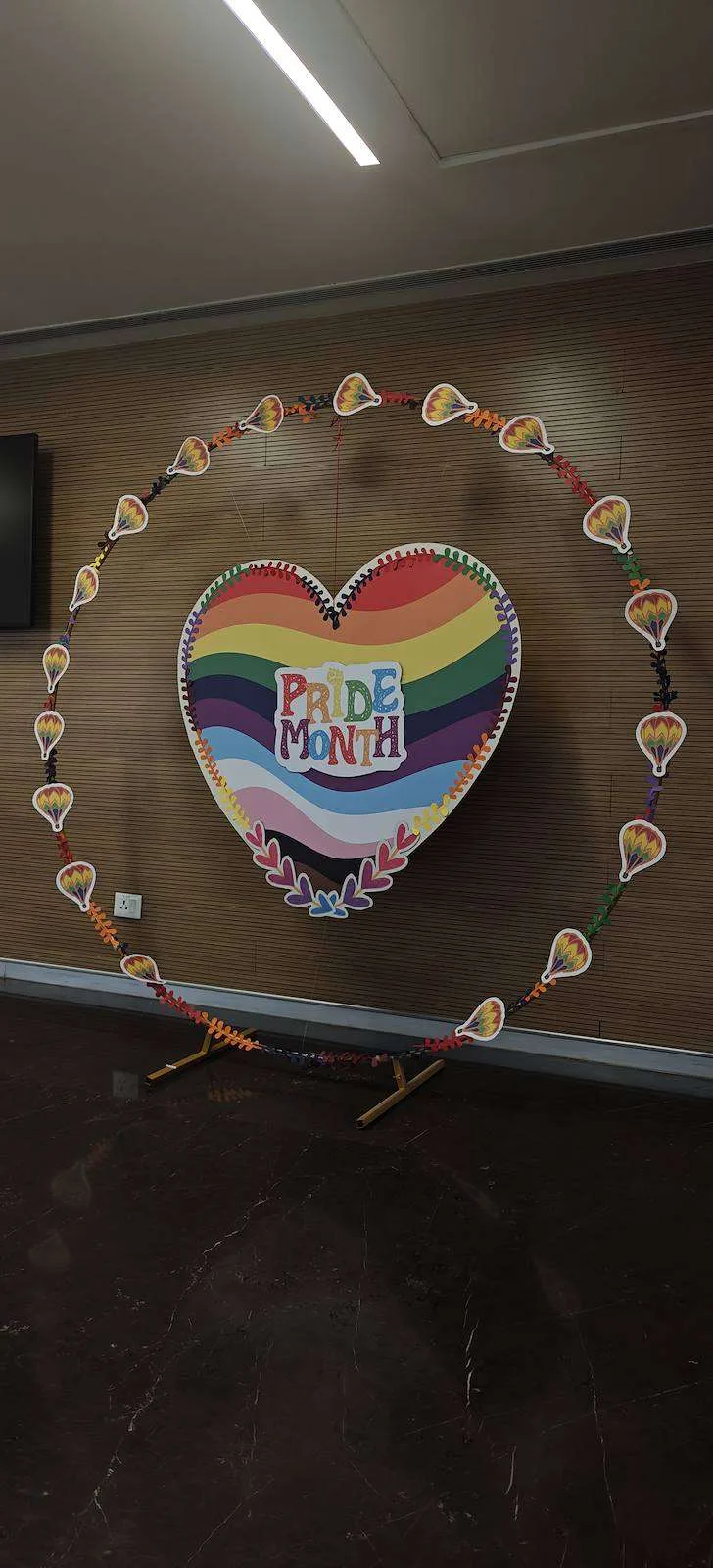 Heart-shaped Pride installation framed by a floral ring